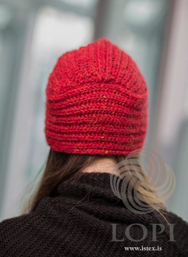 Back view of Höttur in carmine red heather — the strip ends sewn in at the centre back in soft folds, with brioche ribs round the sides. The black knitted top is not part of the pattern