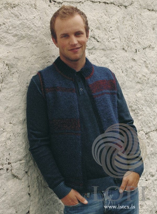 Man in the Boði zip vest — blue Álafosslopi with speckled navy-and-red stripe blocks and a high navy collar with a red line; the dark sweater under it and the jeans are not part of the pattern (shown in the original colour — this kit has space blue for the sapphire blue)