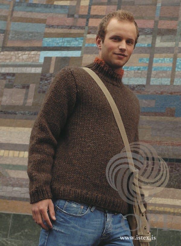 Man in front of a mosaic wall in the brown version of Strax — chocolate Jöklalopi in plain stocking stitch, ribbed hem and cuffs, and a ribbed polo collar with a carrot red tip, shown in the pattern’s original colours (carrot red is no longer made). The canvas shoulder bag and the jeans are not part of the pattern
