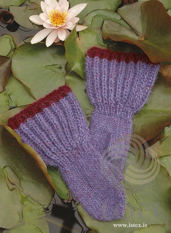 A pair of Bjalla children’s mittens on water-lily leaves — long brioche cuffs with a garnet red top edge, a ribbed wrist and a plain hand (shown in the original colours — this kit has milkyway, a paler lavender, for the lilac)