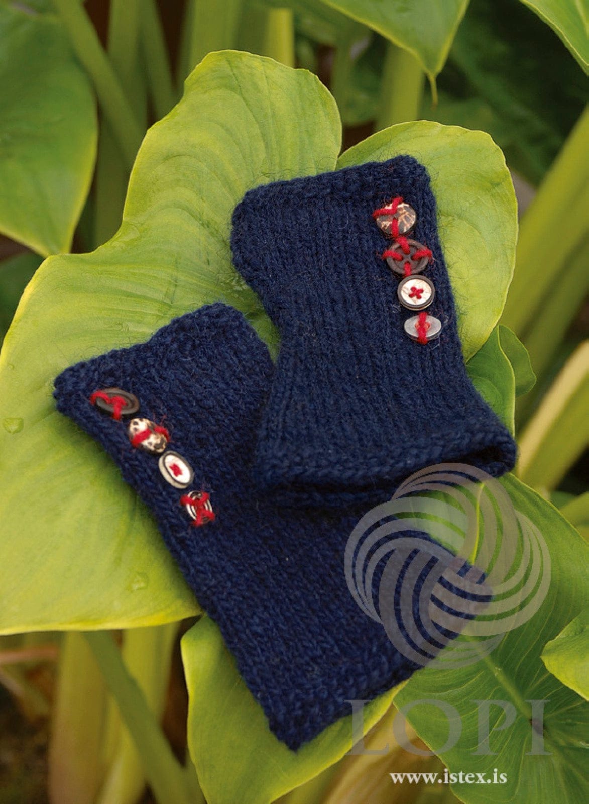 A pair of Stúkur wrist warmers in navy Léttlopi with moss-stitch edges and small buttons sewn along the side