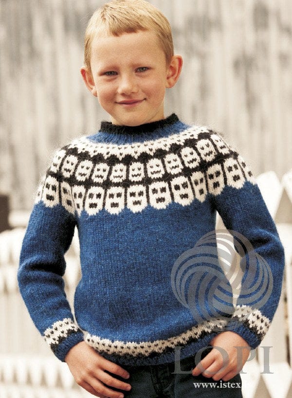 Boy in the blue Fés sweater — white faces with black eyes and mouths on a black band in the yoke