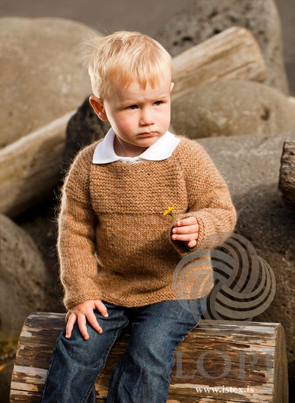 Boy in the barley Kjarr sweater, seated, showing the garter-stitch yoke