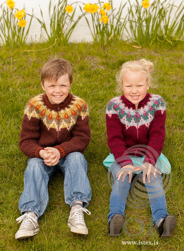 Two children in Kjós cardigans — on the left, the brown colourway in sheep sorrel with a five-colour yoke
