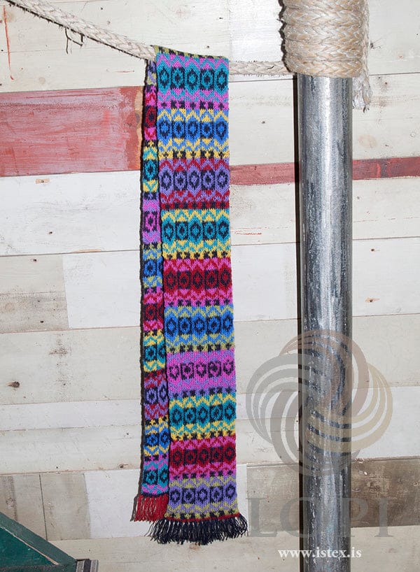Þula scarf in eight colours of Einband, with stripes and small patterns and a fringe at each end, hanging from a pole