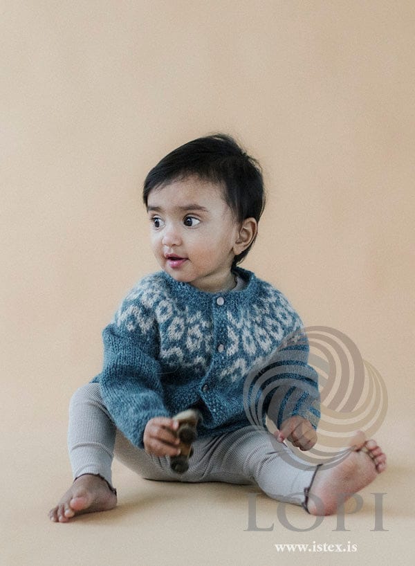 Tryggð baby cardigan with seed-stitch button band, in gulf stream and ivory