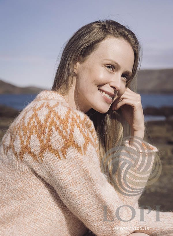 Close view of Mar on a smiling woman — the orange lattice on the pale yoke and the flecked peach sleeve, in the pattern’s own colours