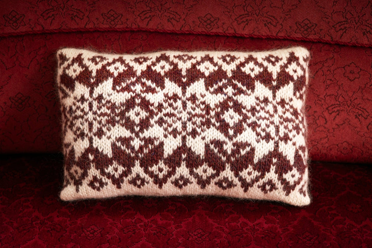 Stjörnuband cushion knitted in Álafosslopi — big ruby red stars on a white ground