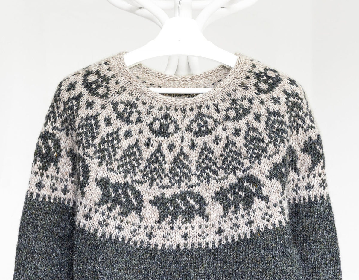 Close-up of the Mishka yoke: a ring of walking bears, fir trees above them, rounded motifs near the neck and a light beige i-cord neck edge