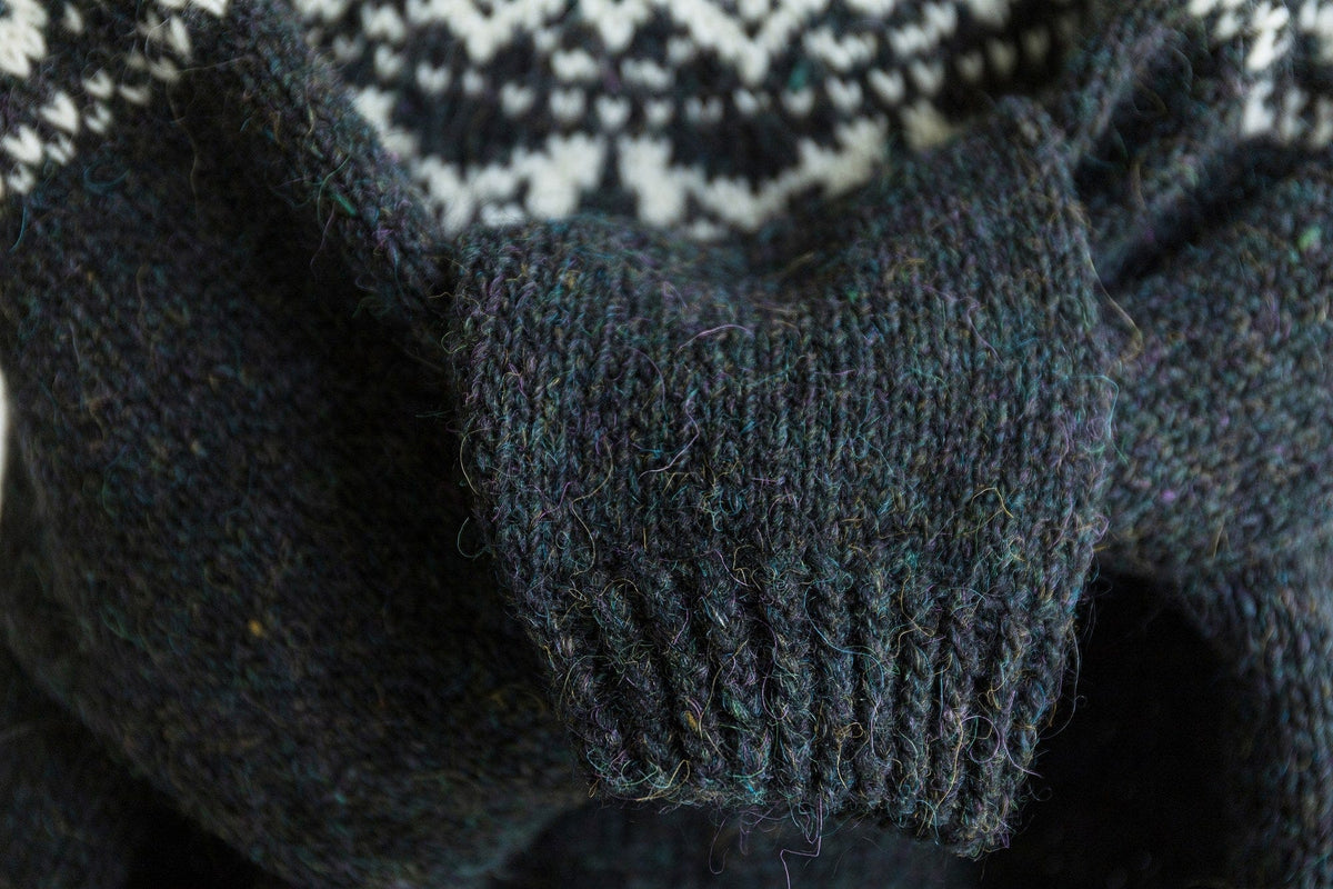Close-up of a Galaxy sleeve and twisted-rib cuff, showing the teal, purple and mustard flecks in the yarn