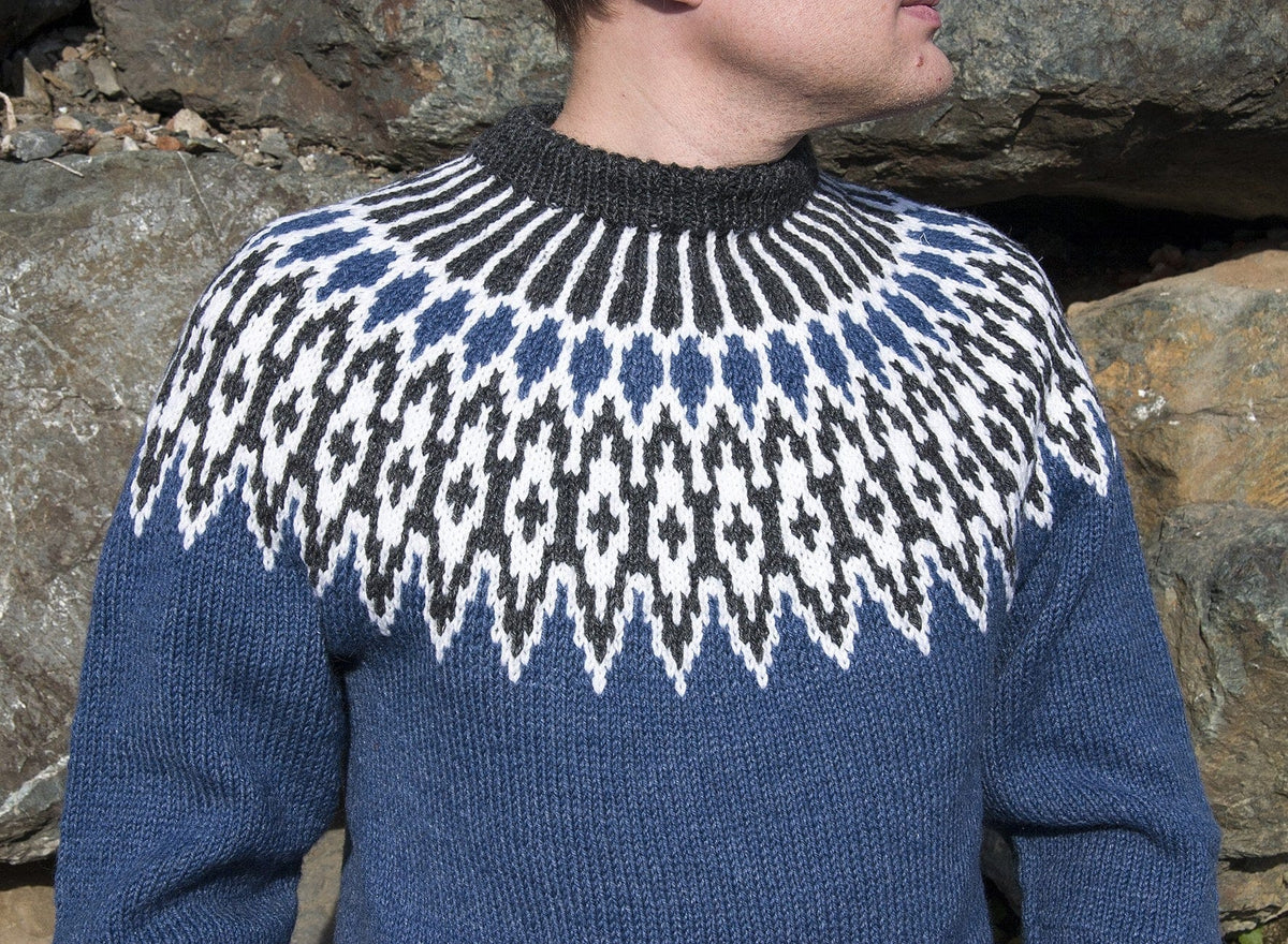 Close-up of the Odin yoke worn in sunlight: white and black heather lozenges, a ring of blue drops and rays up to the black heather neckband