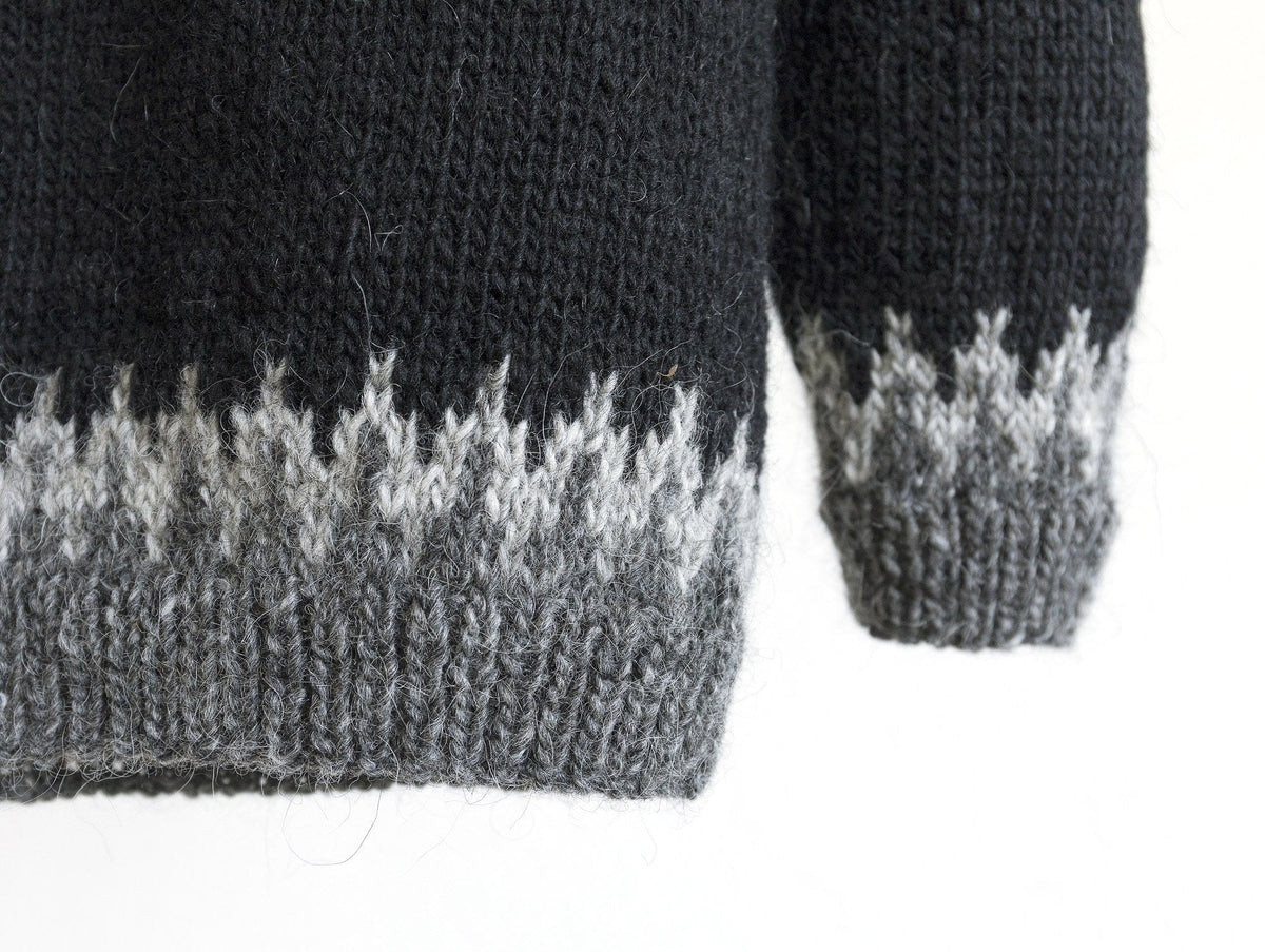 Close-up of the hem and cuff of the black and grey Odin: dark grey rib and an ash zigzag border below the black body