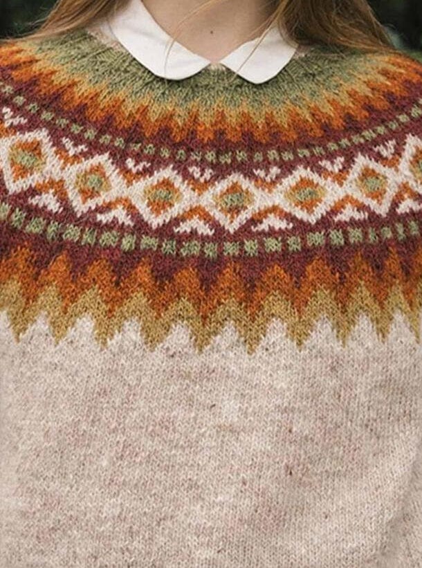 Close view of the Góa yoke in the pattern’s own colours — mustard and ginger zigzag points over the light moorit body, marron bands, moss-and-marron checks, a band of light diamonds with ginger and moss centres, and moss at the neck. The white round blouse collar is not part of the pattern
