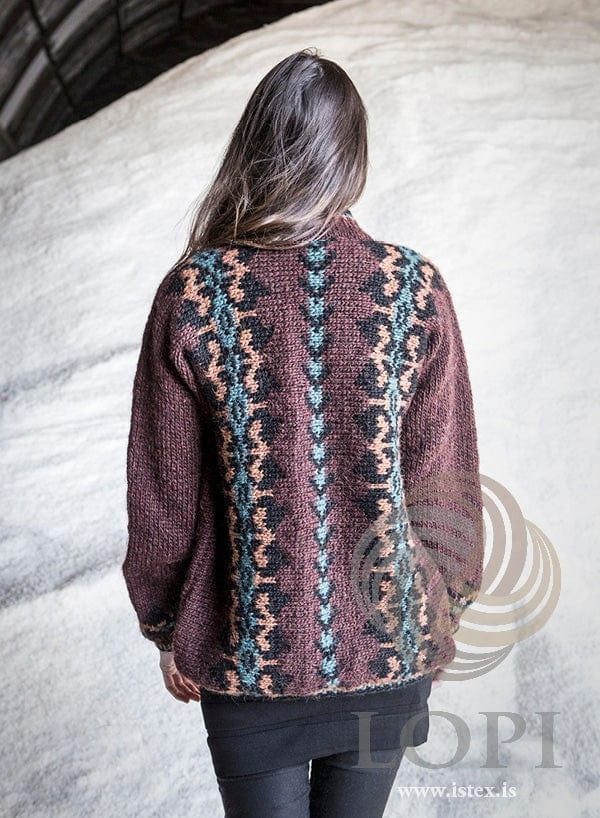 The auburn Lilja from the back, shown in the pattern’s own colours — a teal and black band down the centre back between two black bands with amber and teal motifs. The black dress and leggings are not part of the pattern