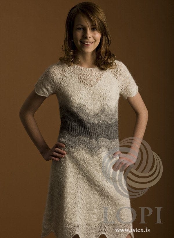 Woman in the white and grey Miðja lace dress with short sleeves — waves of lace shading to a grey ribbed waist