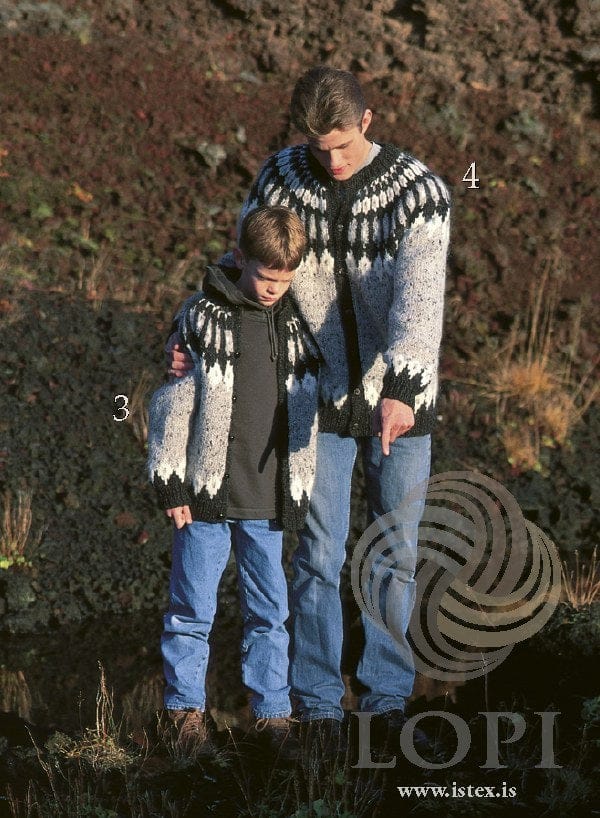 A boy (marked 3) and a young man (marked 4) outdoors, each in one of this pattern’s cardigans, in the original colours — light gray tweed (9451, no longer made) with black heather rib and front bands, small dark buttons, a white and black heather border above the rib, and a yoke of white motifs, a black heather band and long grey and black pillars rising to the neck. The boy’s is open, the man’s buttoned. The boy’s dark hoodie, the man’s grey T-shirt, their jeans and shoes are not part of the pattern