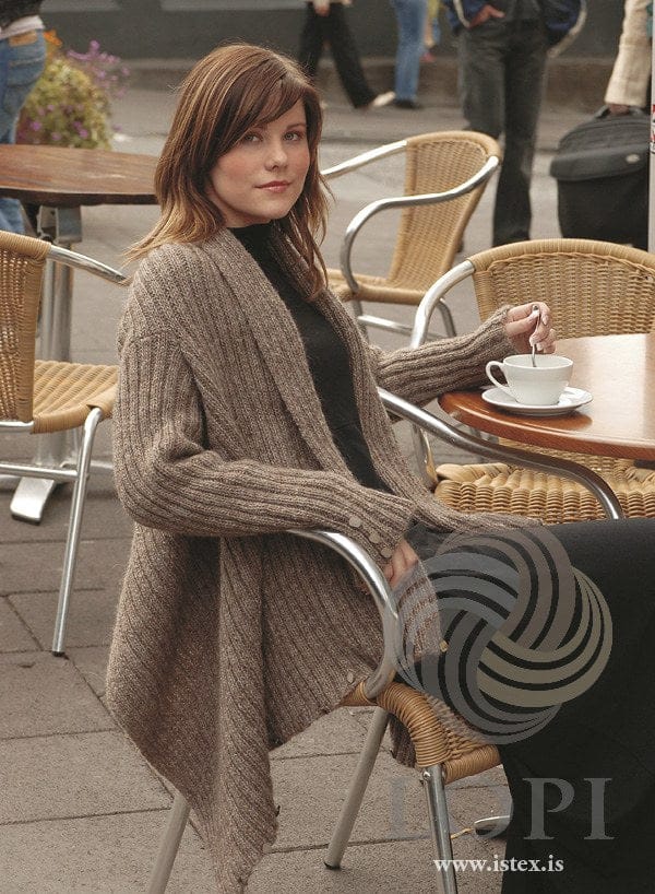 The same Þel pattern in light brown oatmeal, with small buttons along the hem and up the sleeve — sold as a separate kit
