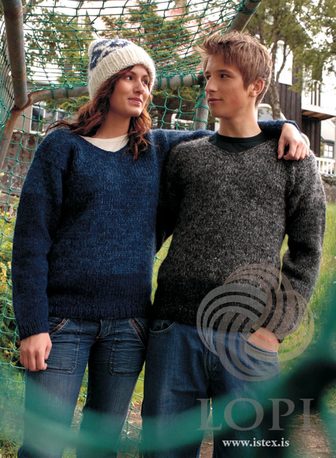 Two people in Húm sweaters — the man in the grey version, dark and tweedy, the woman in the blue version