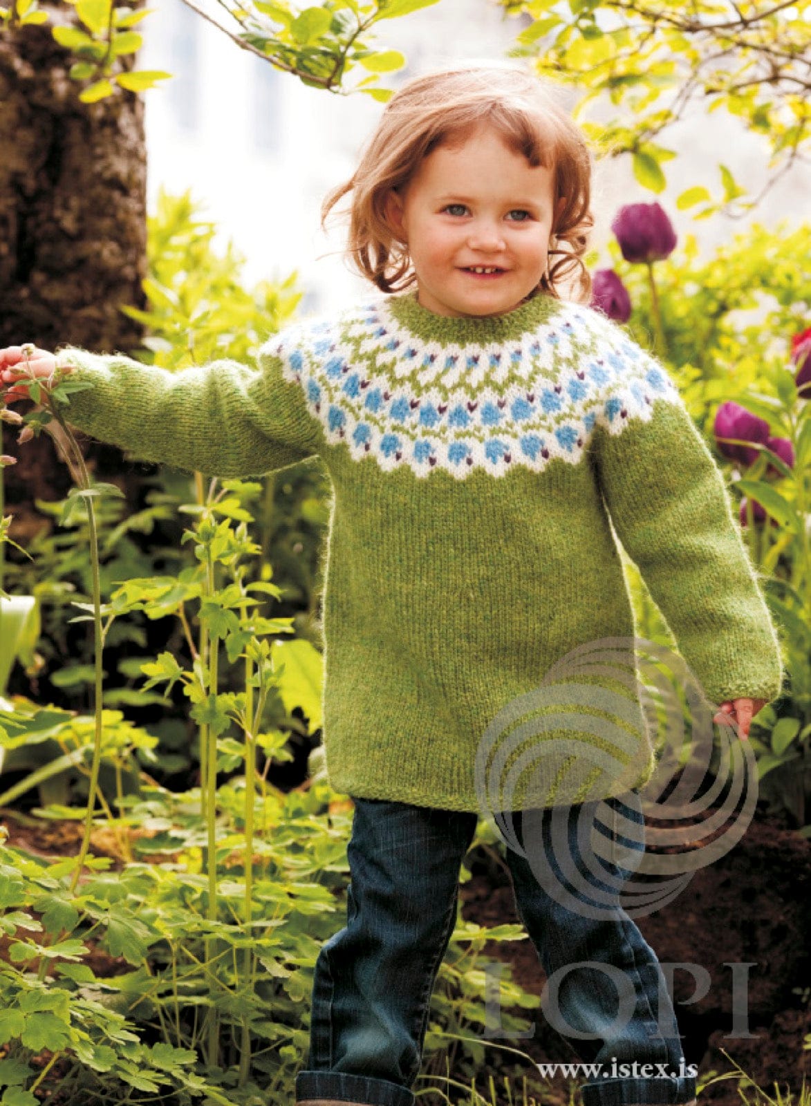Toddler in the green Bláklukka sweater — spring green Léttlopi with a white yoke band of heaven blue bell flowers and violet accents