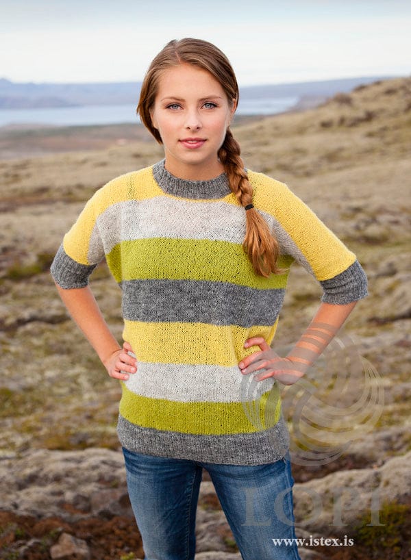 Woman in the Blaka sweater — broad Einband stripes of grey, lime, light ash and yellow with ribbed cuffs