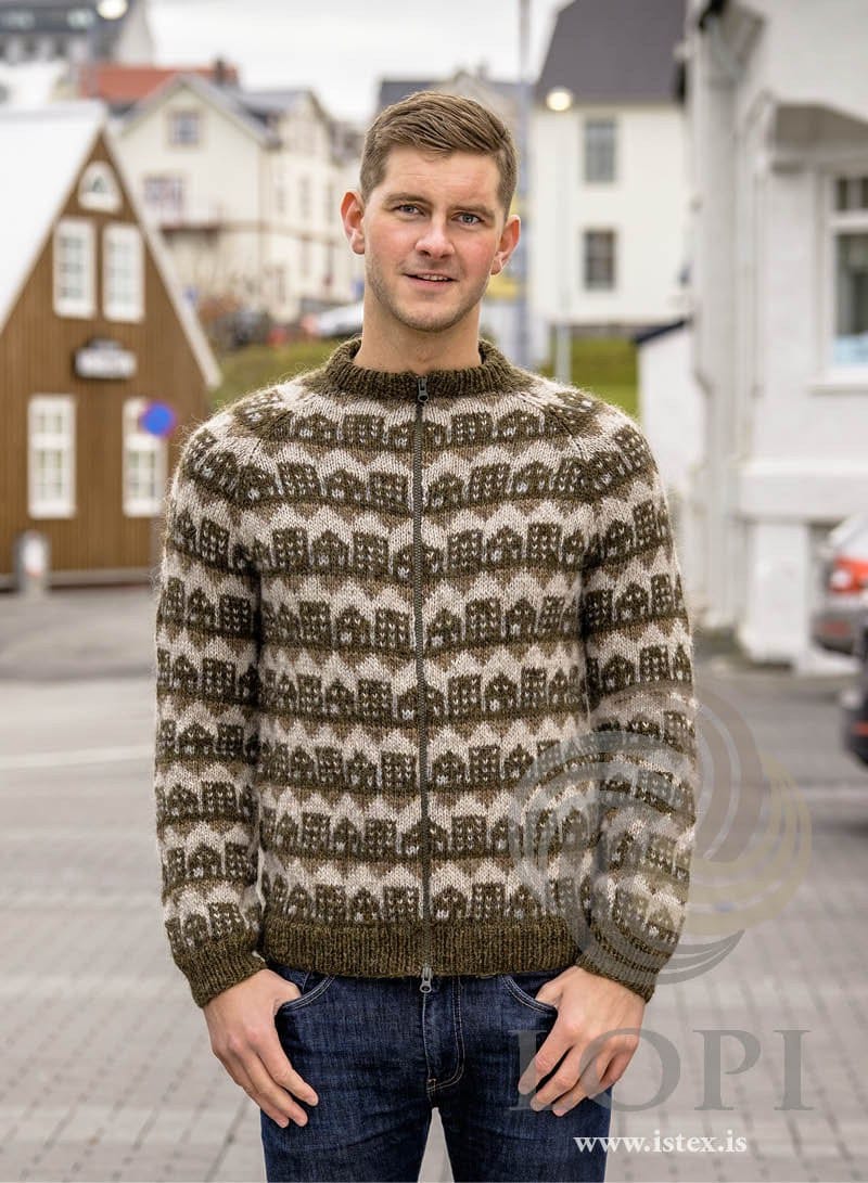 Man on a street of old houses in the brown and green Borg mín borg zip cardigan — little houses with lit windows and zigzag bands