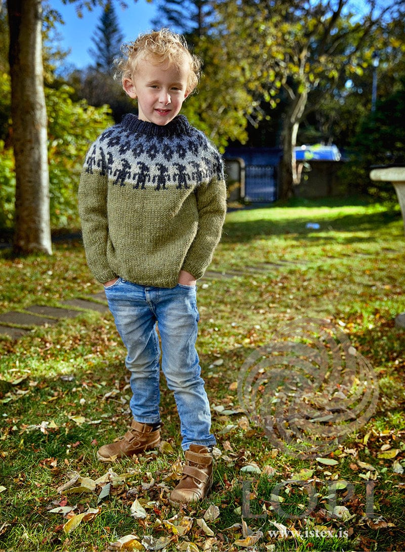 Drekabörn children’s sweater in clover green Plötulopi with a yoke of dark figures on light ash and blue (shown in the original colours)