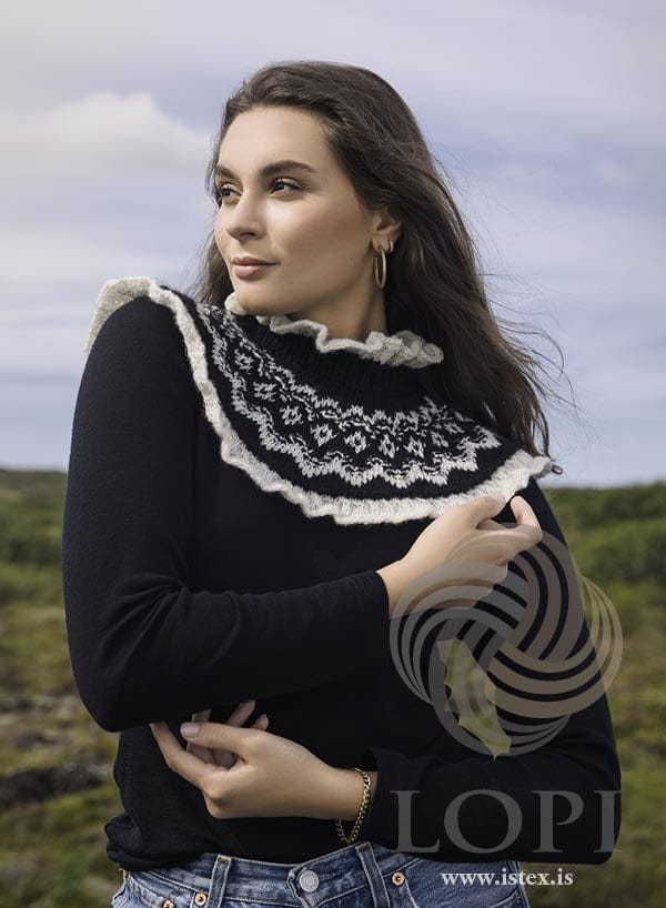 Beta ruffled collar in black Léttlopi with white Einband, worn over a black sweater