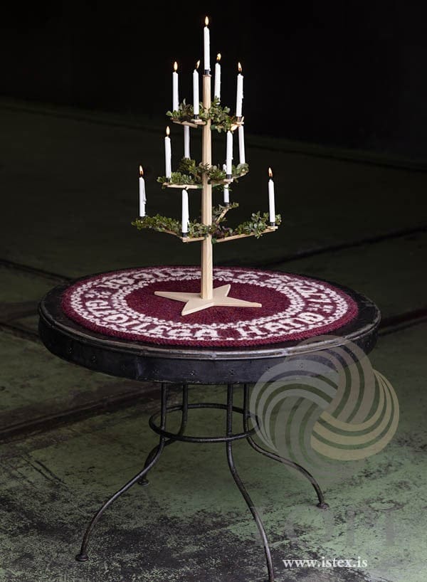Friður knitted round mat on a small table under Christmas candles