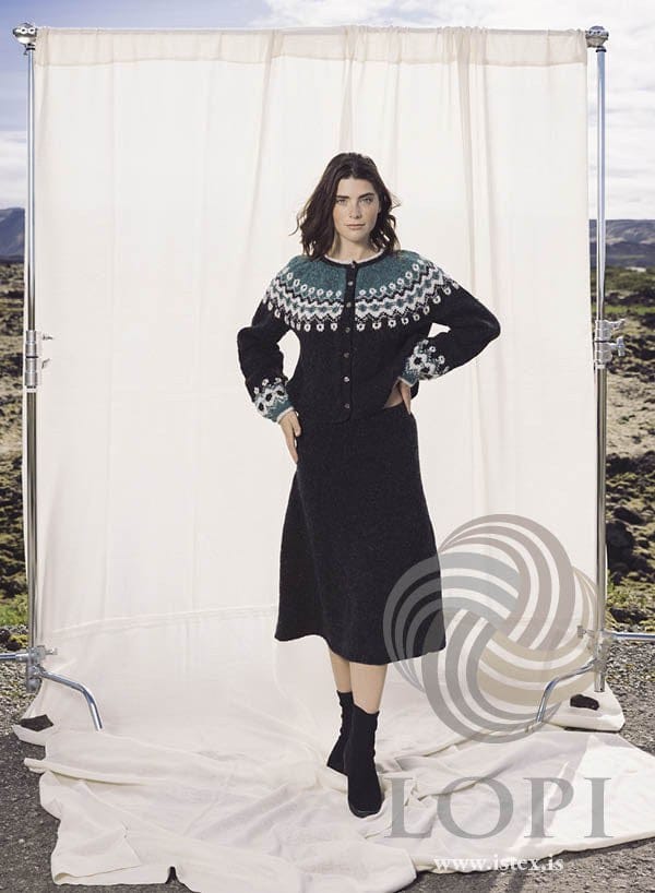 Woman in the Þytur skirt on a lava field; the yoked cardigan she wears is a different pattern